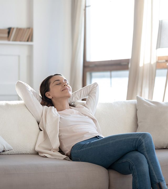 Femme détendue respirant de l’air frais dans son salon