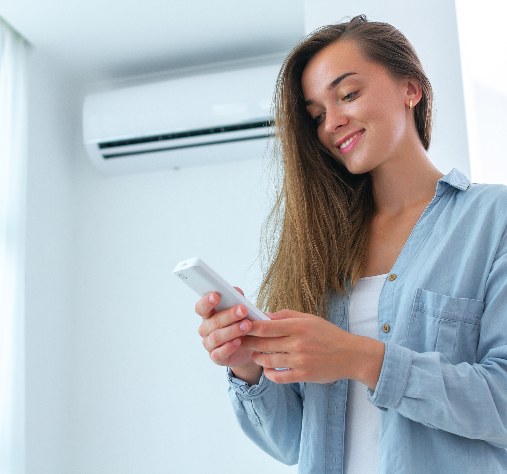 Femme souriante réglant la température d’une thermopompe.