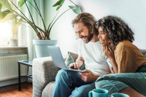 Couple souriant remplissant une demande de soumission en ligne sur un ordinateur portable